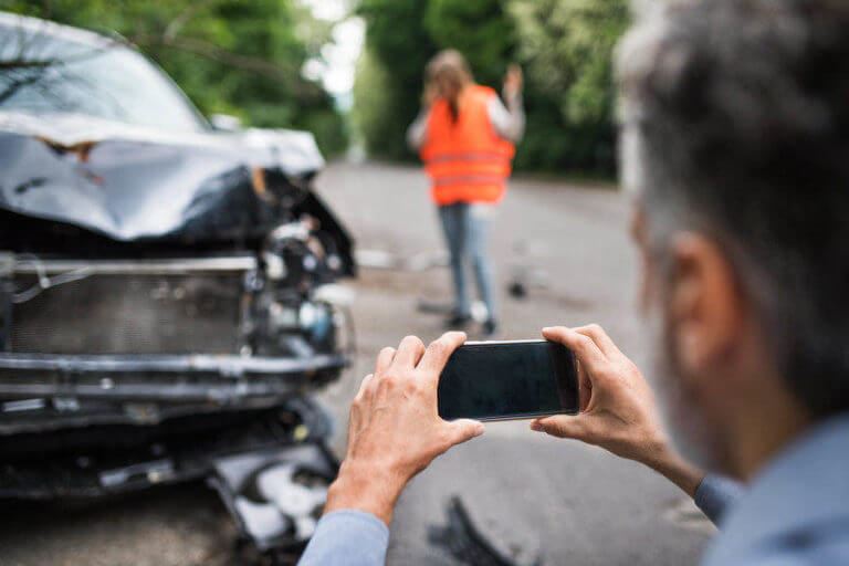 Man taking picture of a broken car