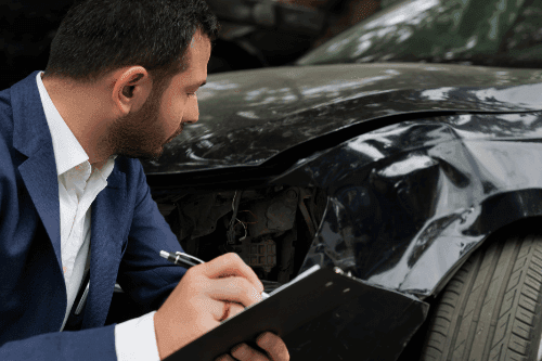man writing down details of car accident on clipboard